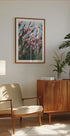 un accogliente soggiorno con un mobile in legno, una poltrona beige, un quadro incorniciato di fiori rosa e una pianta in vaso.