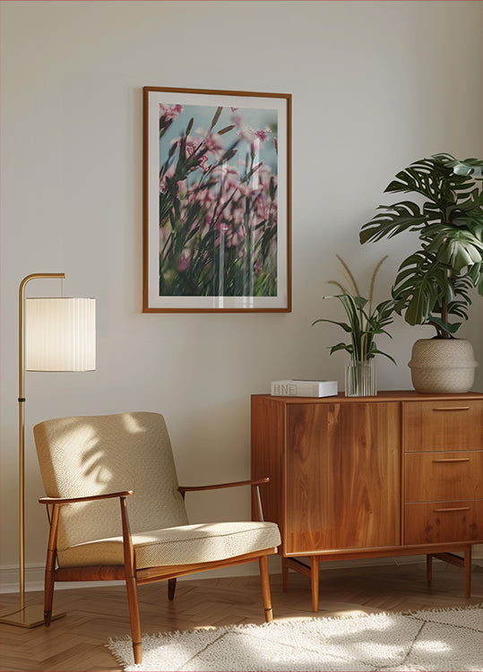 un accogliente soggiorno con un mobile in legno, una poltrona beige, un quadro incorniciato di fiori rosa e una pianta in vaso.