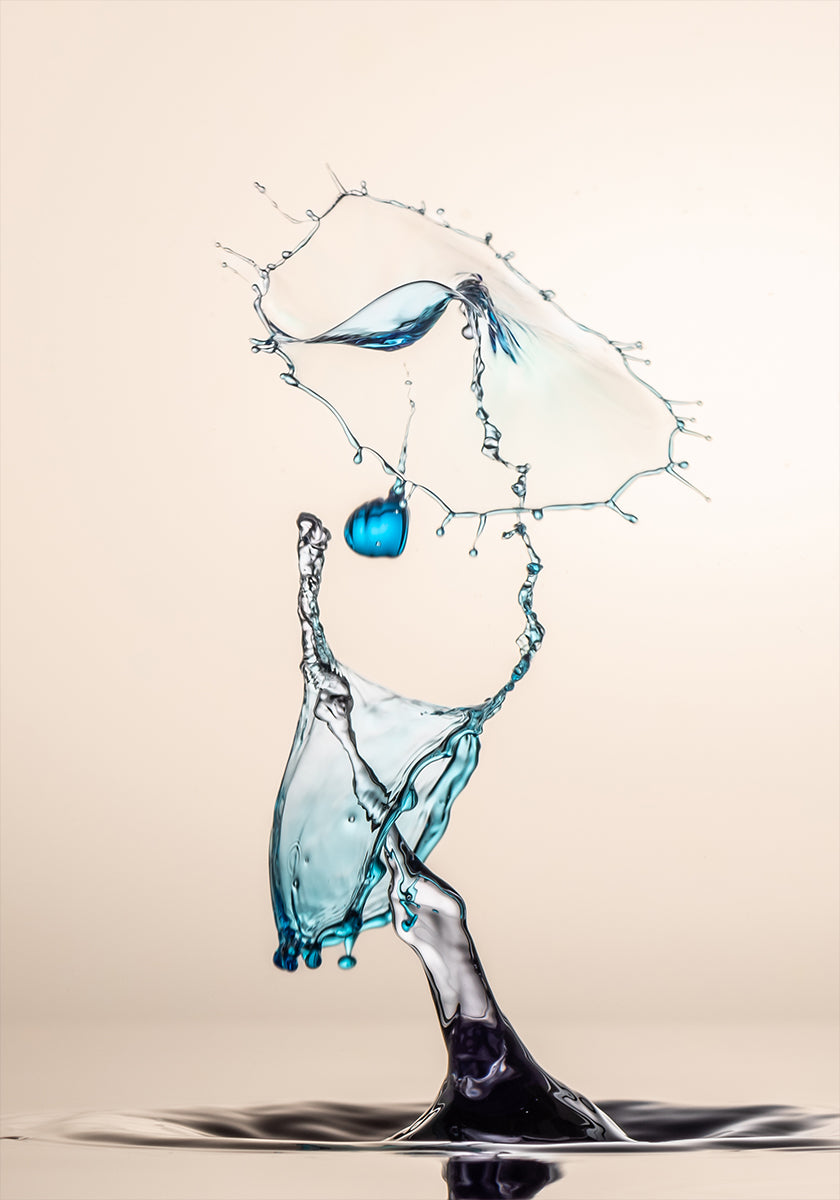uno spruzzo d'acqua dinamico, con un oggetto blu sospeso a mezz'aria e un grande spruzzo d'acqua che cade a cascata, creando un senso di movimento ed energia.
