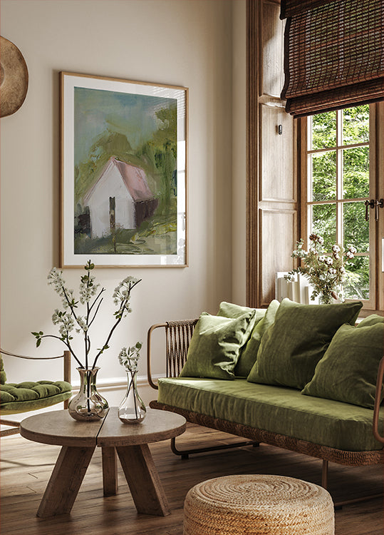 un accogliente soggiorno con una grande finestra, un divano verde, un tavolino in legno e un dipinto incorniciato di una casa.